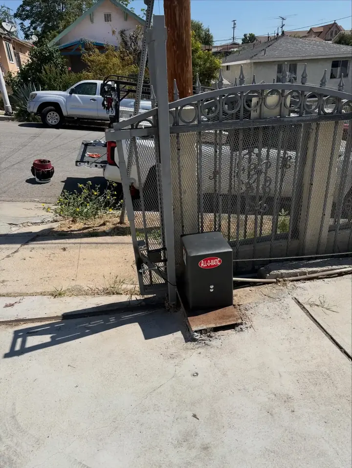 Ornamental iron driveway gate with a gate operator box beside it