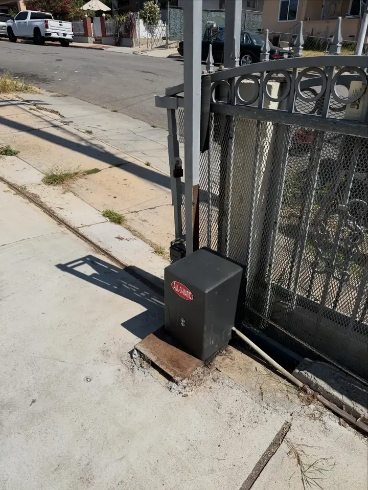 Sliding ornamental iron gate with an operator box beside the track