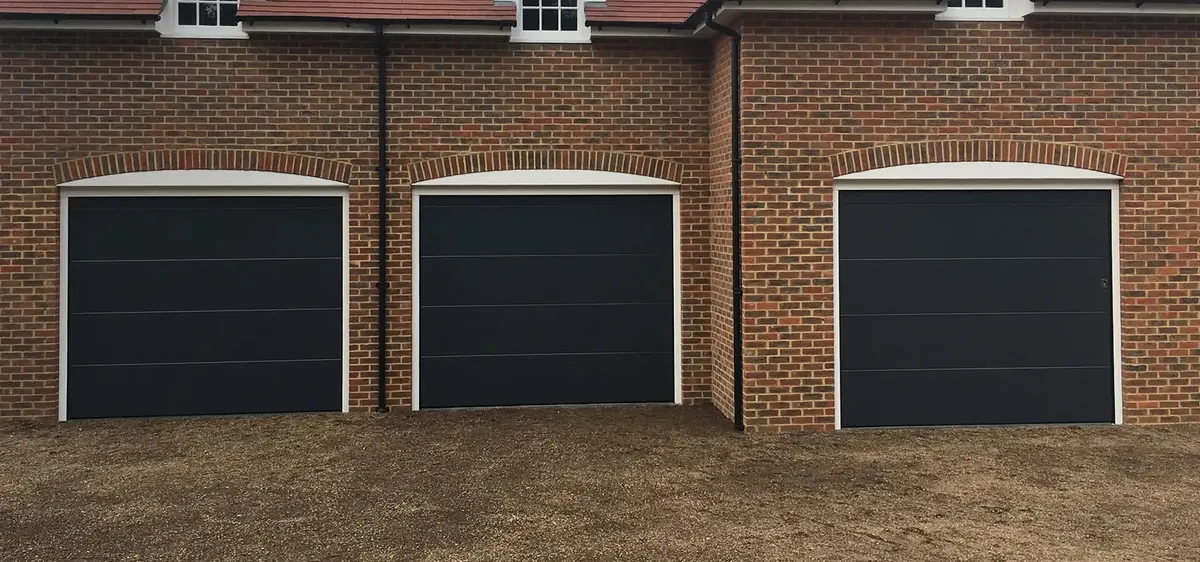 Row of three garage doors on a brick building